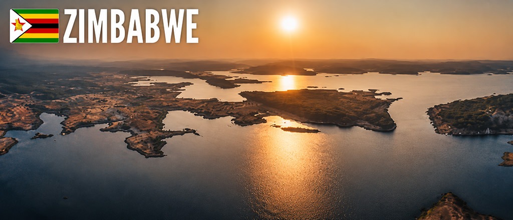 Aerial view over Lake Kariba in Zimbabwe during sunset, with golden reflections on the water, scattered islands and endless horizons stretching into the distance.