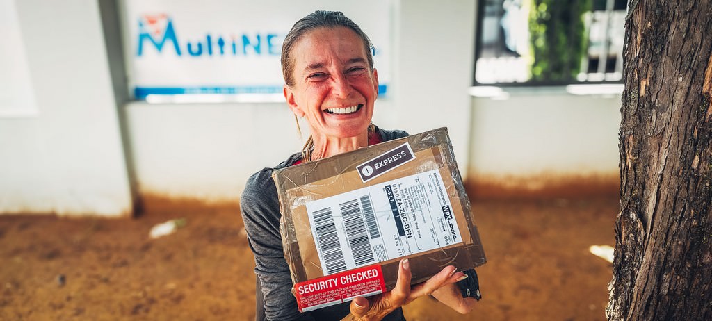 Smiling Fenny holding a DHL Express parcel after successfully receiving an important shipment while traveling through South Africa.