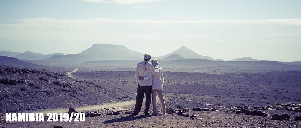 Totti and Fenny standing together in the Namibian desert landscape with mountains in the distance